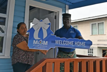 single mom receives the symbolic key to her new home under the MoM programme
